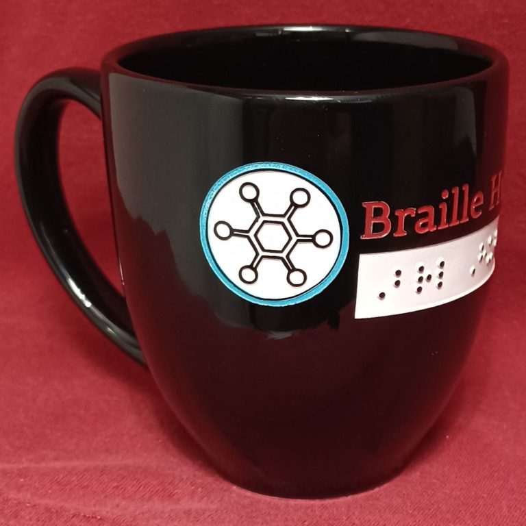 Coffee Mug with etched print and raised braille dots. Black coffee mug with color print and braille etched in the mug. Reads Braille Hub USA.